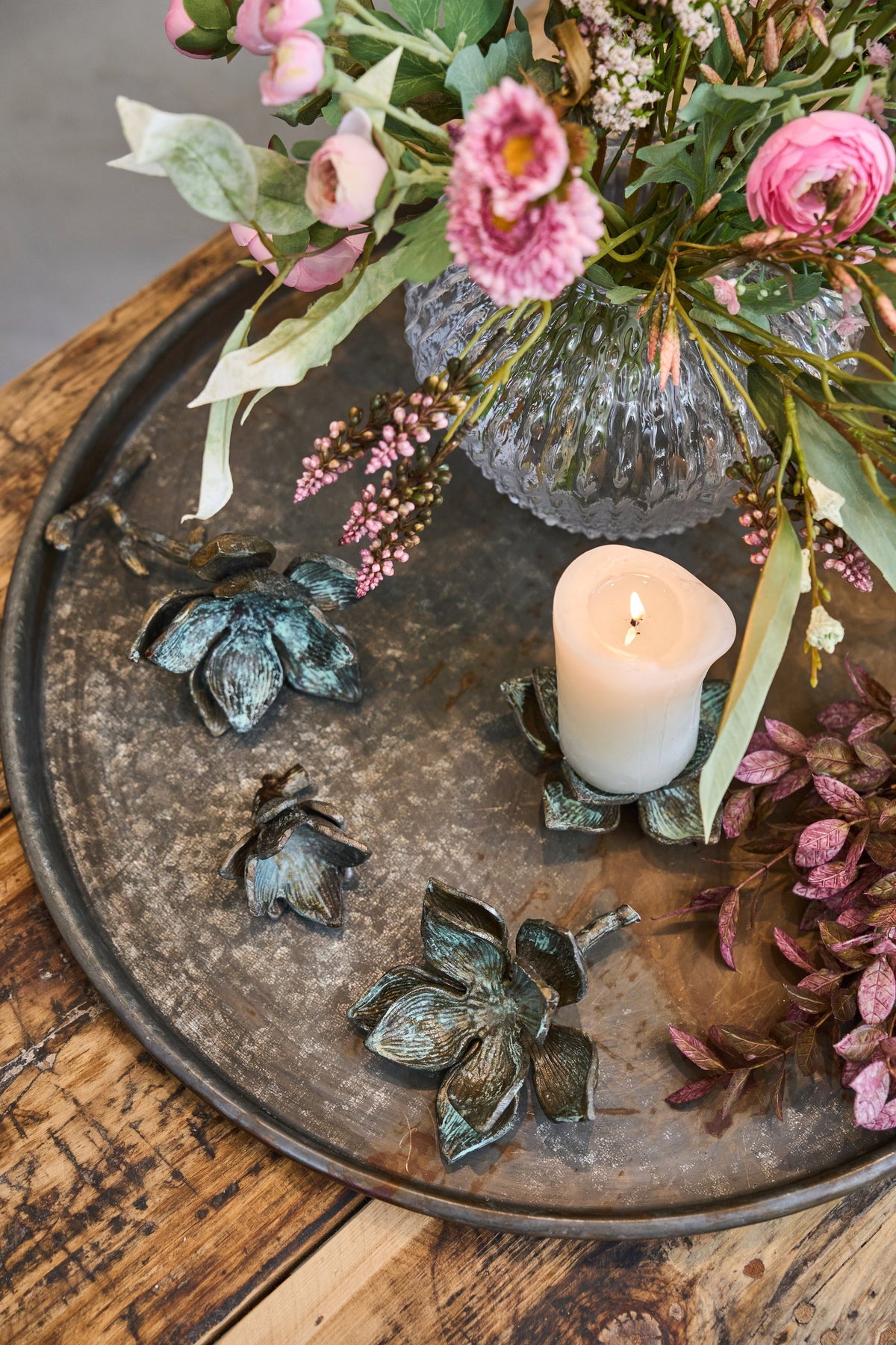 Lotusblomster i metallook på rustik bakke med fyrfadslys og blomster