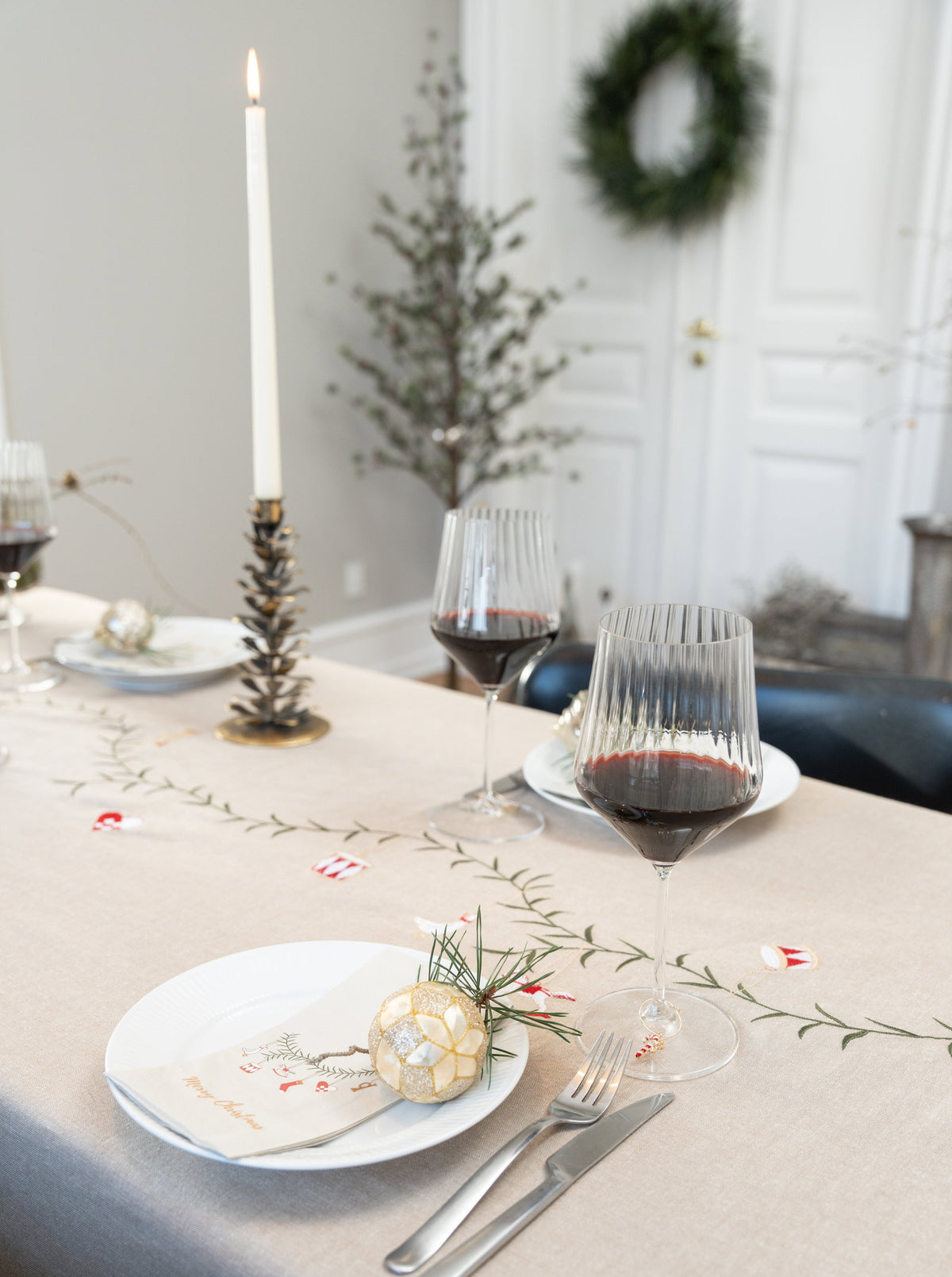 Pyntet julebord med juletræ og krans i baggrunden