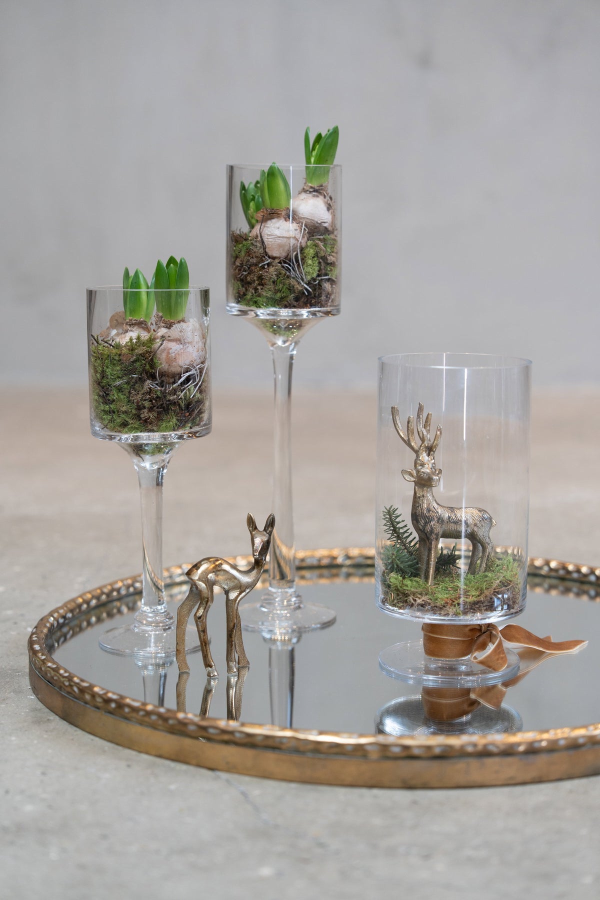 Gyldne krondyr og hjorte på spejlbakke med hyacinter i glas