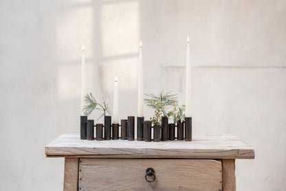 Rørvase med kronelys og små planter på en kommode