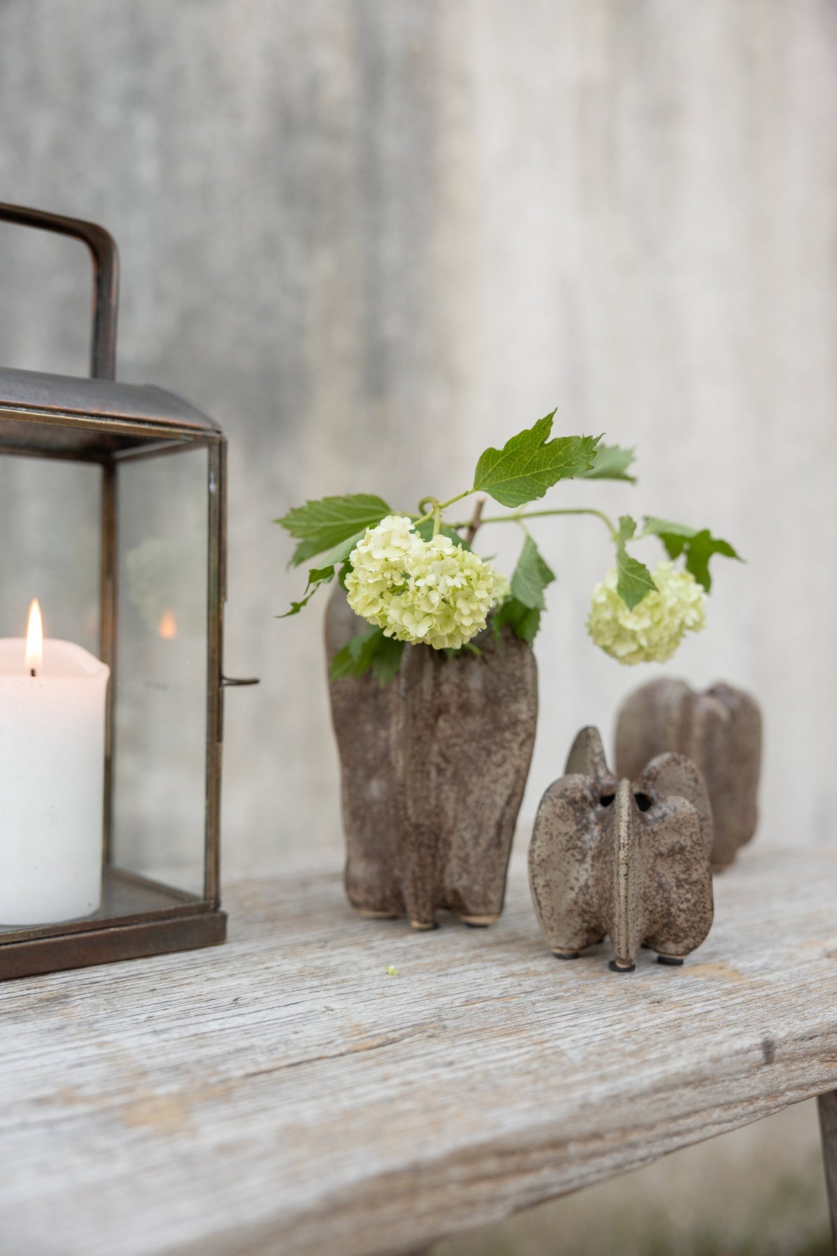 Stentøjsvaser med hvide blomster ved siden af en lanterne